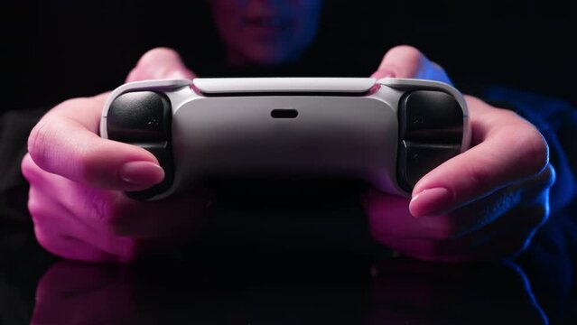 Woman playing video simulator game on console TV with joystick, dark room with neon. Exciting gamer with joypad controller plays soccer, newest wireless gamepad. Hobby, e-sport, 