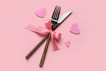 Cutlery for Valentine's Day with bow and hearts on pink background