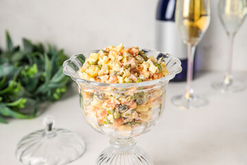 Glass bowl of Olivier salad on white table, closeup