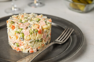 Plate of Olivier salad on white table, closeup