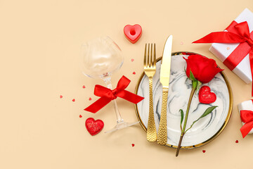 Table setting for Valentine's Day with red rose and gifts on beige background