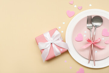 Table setting for Valentine's Day with pink hearts and gift on beige background