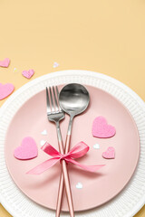 Table setting for Valentine's Day with bow and pink hearts on beige background, closeup