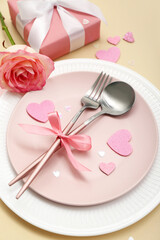 Table setting for Valentine's Day with pink rose and gift on beige background