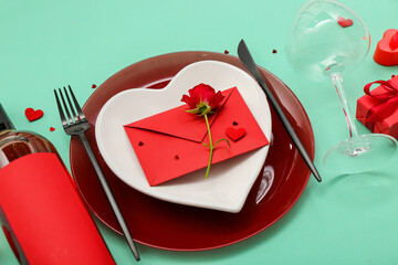 Table setting for Valentine's Day with envelope and rose on green background