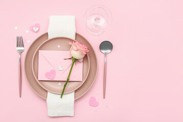 Table setting for Valentine's Day with envelope and rose on pink background