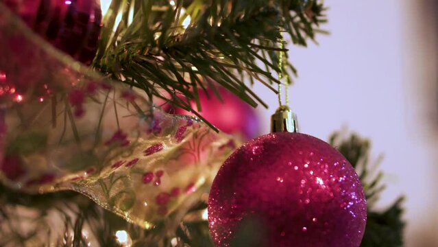 Red ball and golden ribbon ornaments on christmas tree with blinking lights