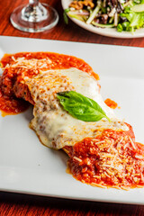 Chicken Parmesan or parmigiana. Italian comfort dish. Chicken breast covered in breadcrumbs fried, topped with marinara sauce, melted mozzarella, parmigiana and provolone cheeses and Italian parsley.