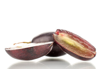 Two halves and one whole berry of black grapes, close-up, isolated on white.