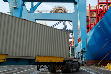 Fototapeta na wymiar Port container terminal with container ship in background and white container in foreground