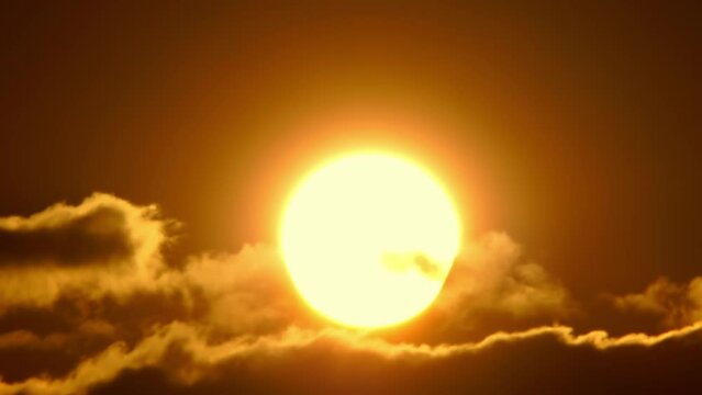 Cinematic view of orange yellow and red sunset sky with clouds. End of the day. Dusk at summer time after rain. Epic sun set with large circle as sun goes down to twilight. Evening sky.