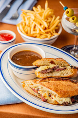 Reuben Sandwich. Classic traditional American sandwich. Pastrami and corned beef on grilled rye bread, melted Swiss cheese, sauerkraut, topped with thousand island dressing served french fries.