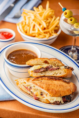 Reuben Sandwich. Classic traditional American sandwich. Pastrami and corned beef on grilled rye bread, melted Swiss cheese, sauerkraut, topped with thousand island dressing served french fries.