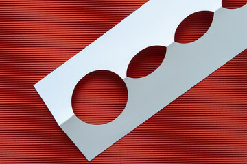 folded paper object with circle or oval cutouts on red brown corrugated paper