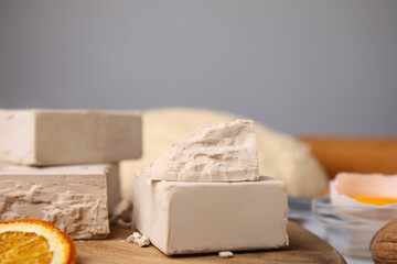 Blocks of compressed yeast and ingredients on wooden table, closeup
