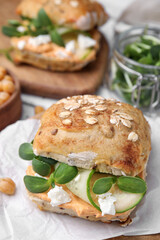 Delicious sandwich with hummus, microgreens and cucumber slices on white table, closeup