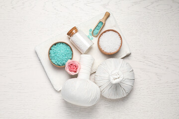 Flat lay composition of herbal bags and spa products on white wooden table