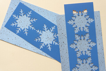 blue paper stencils with snowflake cutouts on holiday cards