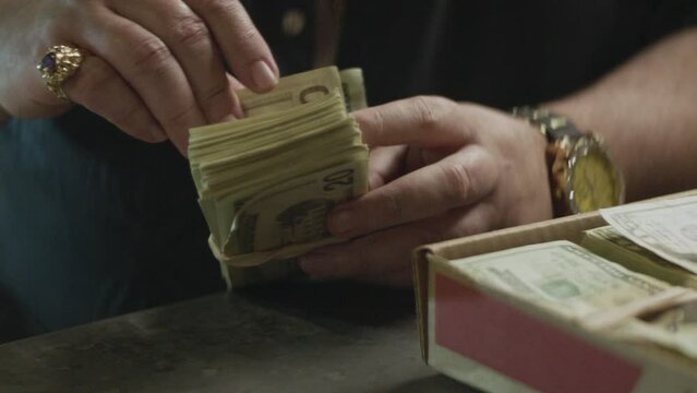 A mafioso man counting a stack of cash
