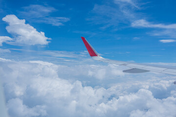 Airplane wing flying above the sky with white clouds. View from aircraft window. flying and traveling concept.