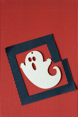 halloween ornament (of a ghost or goblin) and black paper frame on red brown corrugated paper
