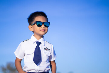 A boy wearing dark glasses in a pilot suit on a blue tone background