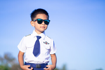 A boy wearing dark glasses in a pilot suit on a blue tone background