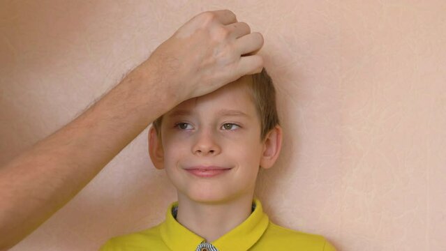 portrait of a happy caucasian boy 7-8 years old whose dad measures his height making a mark on the wall. children grow up fast. home interior, son's height measurement