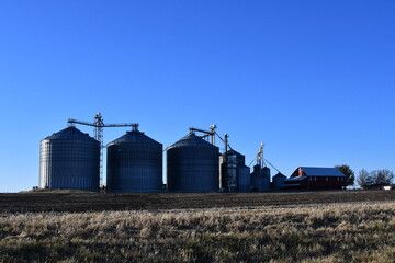 Fototapeta na wymiar Grain Bins and a Barn in a Farm Field