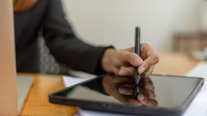 Closeup hand signing or using a digital pen on a computer tablet on the desk, a businesswoman use a...