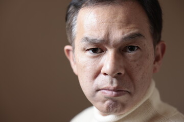 Middle-aged Asian man in white turtleneck wool sweater under gray background. Concept image of Warm Biz, stability in daily life, and sustainable living.