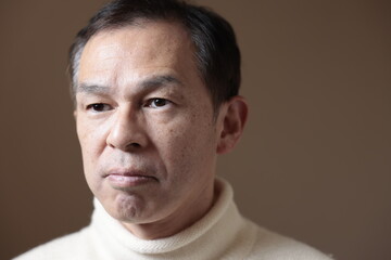 Obraz premium Middle-aged Asian man in white turtleneck wool sweater under gray background. Concept image of Warm Biz, stability in daily life, and sustainable living.