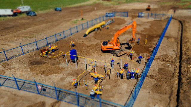 Aerial View Excavator And Construction Workers Working On Construction Site In Open Field. Pipe Laying In Trench For Gasification. Top Point Of Shooting. Tilt Shift Effect. Thumbnail With Blur..