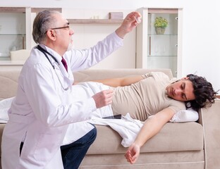Old male doctor visiting young male patient