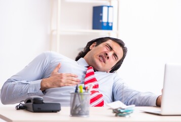 Young male employee suffering in the office