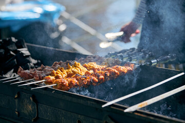 Cooking pork barbecue with skewers cubes of meat on BBQ grill, traditional Eastern Europe and...