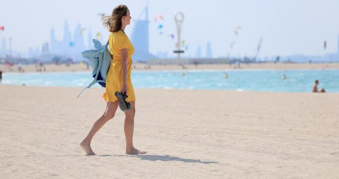 Tourist girl walks on the beach with a backpack in Dubai