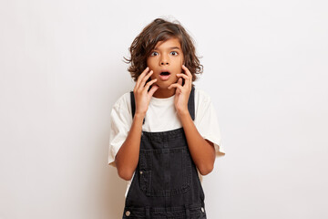 dumbfounded young dark-skinned guy with curly hair, dressed in overalls and a white t-shirt