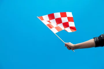 Poster Human hand waving checkered flag on blue background © xy