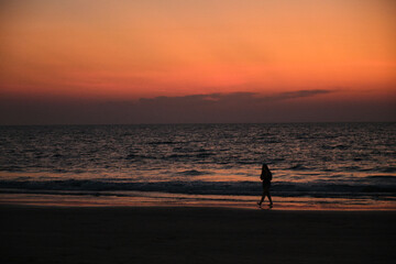 Fototapeta premium Sunset over the sea, waves and silhouettes.