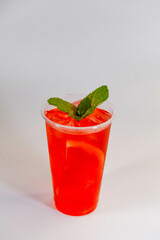 Red lemonade with grapefruit, ice and mint on a white background