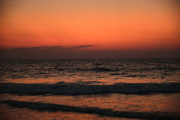 Fototapeta na wymiar Sunset over the sea, waves and silhouettes.
