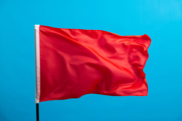 Fototapeta na wymiar Red flag waving on blue background