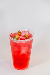 Red lemonade with ice and yellow rose buds on a white background.