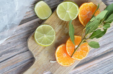 Fototapeta na wymiar wooden cutting board with sliced citrus fruit, lime and mandarin orange