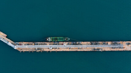 Aerial view of oil tanker docked at industrial port terminal, showing precise marine logistics and...