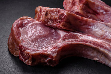 Fresh raw pork meat on the ribs with spices and herbs on a wooden cutting board