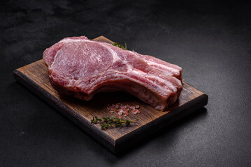 Fresh raw pork meat on the ribs with spices and herbs on a wooden cutting board
