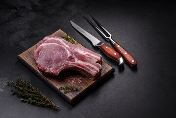 Fresh raw pork meat on the ribs with spices and herbs on a wooden cutting board