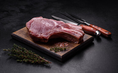 Fresh raw pork meat on the ribs with spices and herbs on a wooden cutting board